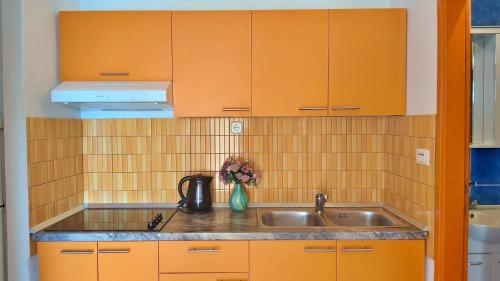 een keuken met oranje kasten en een wastafel bij Apartments Neda in Omiš
