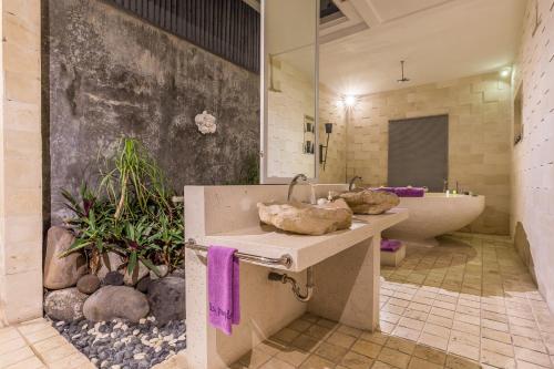 a bathroom with a sink and a bath tub at Villa Purple in Legian