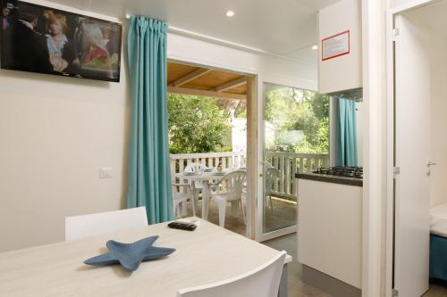 eine Küche und ein Esszimmer mit einem Tisch, einer Küche und einem Balkon in der Unterkunft Camping Casa Di Caccia in Marina di Bibbona