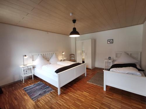 - 2 lits blancs dans une chambre dotée de parquet dans l'établissement Bauernhaus am Limes, à Altmannstein