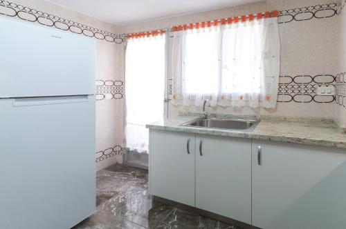 a white kitchen with a sink and a window at Acapulco IV in Gandía