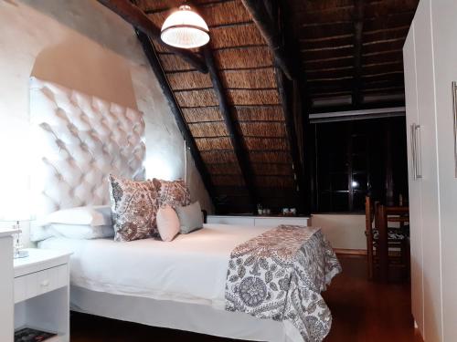 a bedroom with a white bed with a large headboard at Little Tree Loft in Uitenhage