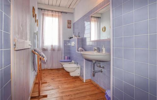 Baño de azulejos azules con aseo y lavamanos en Nice Home In Castelnuovo Calcea With Kitchen, en Castelnuovo