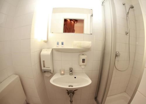ヴィスマールにあるHotel Bertramshofの洗面台とシャワー付きの白いバスルーム