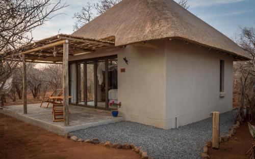 a small hut with a thatched roof and a patio at Ukuthula Bush Lodge in Hoedspruit
