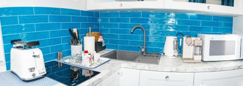 a kitchen with a sink and a blue tiled wall at Apartamenty Hexus - Ofiar Oświęcimskich - Wrocław centrum Rynek in Wrocław