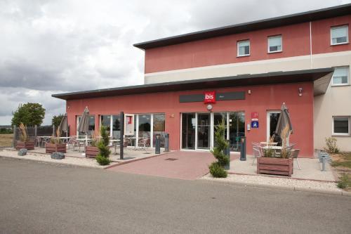 ibis Albert Pays de Somme في ألبرت: مبنى احمر به طاولات وكراسي خارجه