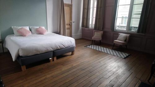 a bedroom with a bed with white sheets and pink pillows at La Menuiserie in Épernay