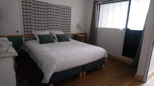 a bedroom with a white bed with pillows and a window at La Menuiserie in Épernay