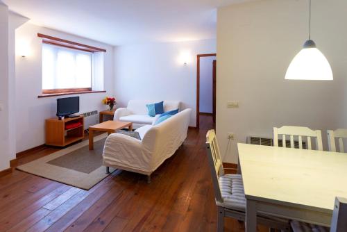 a living room with white chairs and a table at Apartamentos Rentarán in Tredós