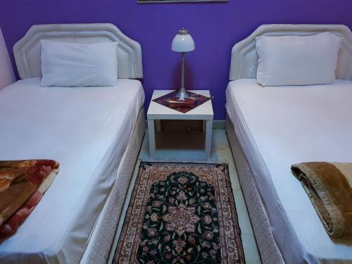 two beds in a room with a table with a lamp at Al Jazeera Hotel Apartments LLC in Dubai