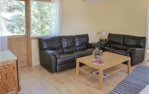 a living room with a black leather couch and a table at Four-Bedroom Holiday Home In Trosa in Trosa