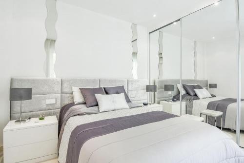 a white bedroom with two beds and a mirror at Charming 1BR Apartment In Heart Of Monaco in Monte Carlo