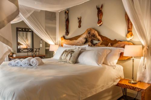a bedroom with a large white bed with a wooden headboard at Ukuthula Bush Lodge in Hoedspruit