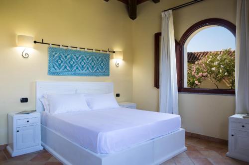 um quarto com uma cama branca e uma janela em Cala Luas Resort em Cardedu