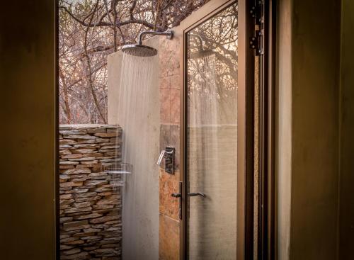 a shower with a glass door next to a window at Ukuthula Bush Lodge in Hoedspruit