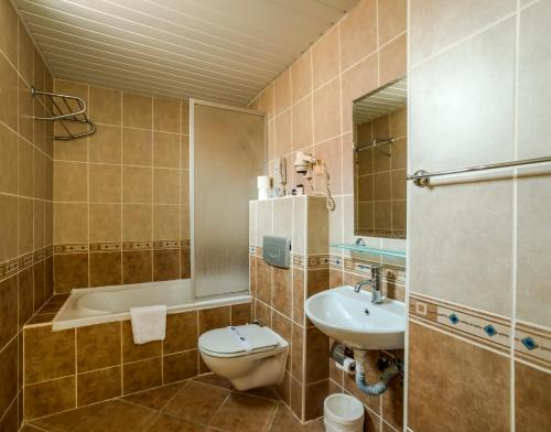 a bathroom with a toilet and a sink and a tub at Santa Marina Hotel in Antalya