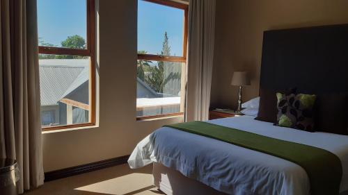 ein Schlafzimmer mit einem Bett und einem großen Fenster in der Unterkunft Karoo Sun Boutique Guest House in Oudtshoorn