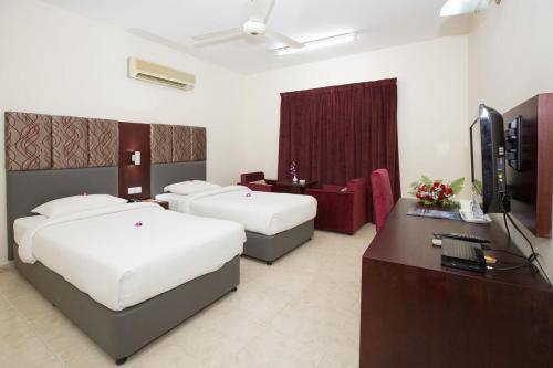 a hotel room with two beds and a desk at Samara Hotel in Muscat