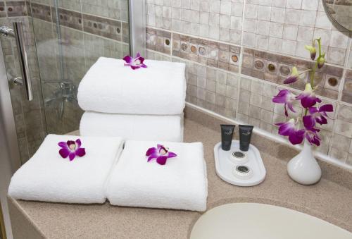 a bathroom with towels and flowers on a counter at Samara Hotel in Muscat
