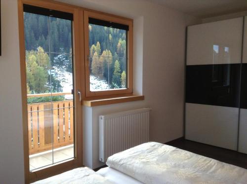 ザムナウンにあるChasa Sulai Appartementsのベッドと大きな窓のある寝室
