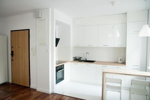 a kitchen with white cabinets and a table and chairs at Apartament Verde in Łódź