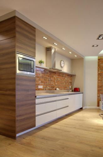 a large kitchen with wooden cabinets and a brick wall at Apartamentowiec Panorama Gór City Center Family&Pet-friendly in Szklarska Poręba