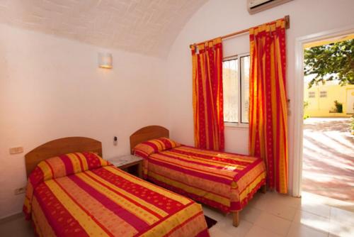 two beds in a room with a window at Samira Club Family and couples only in Hammamet