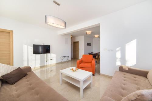 a living room with a couch and an orange chair at Apartments Zvonik in Brist