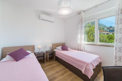 two beds in a room with a window at Apartments Zvonik in Brist