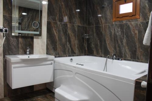 a bathroom with a white tub and a sink at Ayder Hasimoglu Hotel in Ayder Yaylasi
