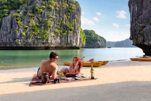 a man and a woman sitting on the beach at Indochine Cruise Lan Ha Bay in Ha Long
