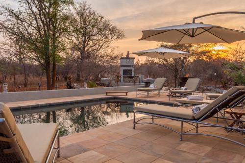 a pool with chairs and umbrellas on a patio at Ukuthula Bush Lodge in Hoedspruit