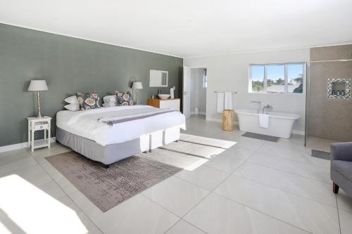 a bedroom with a large bed and a tub and a sink at 269 on Main Holiday Home in Hermanus