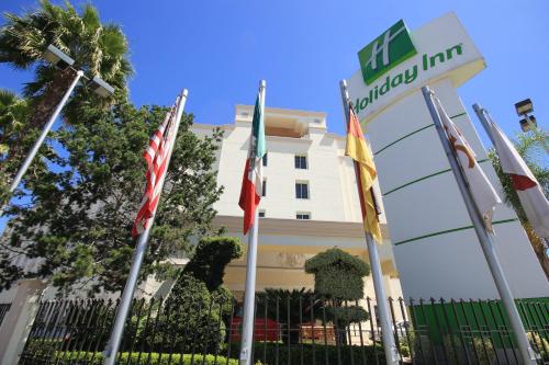 a hotel with flags in front of a building at Holiday Inn Leon-Convention Center by IHG in León