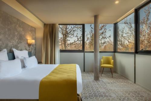 a bedroom with a large bed and a yellow chair at Domaine du Gouverneur, Hôtel, Restaurant & Golf in Monthieux