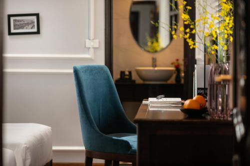 1 dormitorio con silla azul, escritorio y lavamanos en Maya Boutique Hotel & Spa, en Hanói