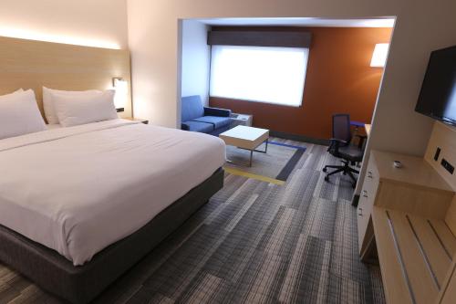 a hotel room with a bed and a chair and a television at Holiday Inn Express - Biloxi - Beach Blvd by IHG in Biloxi