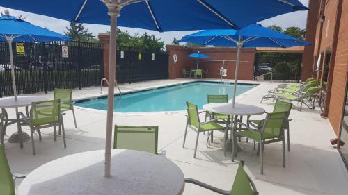 a pool with tables and chairs and blue umbrellas at Holiday Inn Express Baltimore BWI Airport West by IHG in Hanover