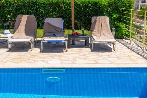 three chairs sitting next to a swimming pool at Astra Villas in Skala Kefalonias