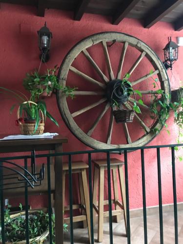 una rueda de carro de madera sobre una pared con dos mesas y macetas en Hotel Rural El Alberche, en Burgohondo