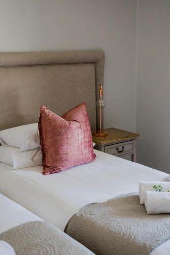 a bed with a pink pillow on top of it at Elianthe Guesthouse in Swellendam