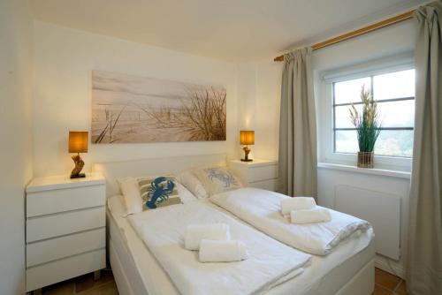韋斯特蘭的住宿－Robben Hüs，卧室内的一张白色床,设有窗户
