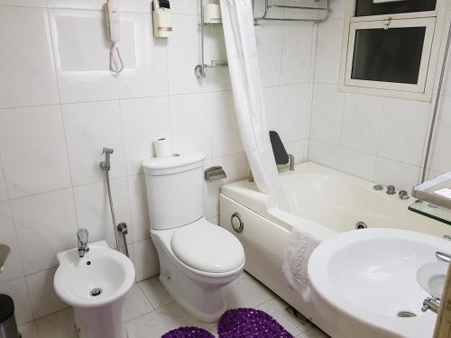 a white bathroom with a toilet and a sink at Al Jazeera Hotel Apartments LLC in Dubai