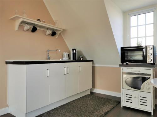 uma cozinha com armários brancos, um lavatório e um micro-ondas em Spilburg Apartments em Wetzlar