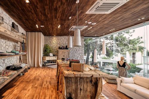 a woman standing in a living room with a large wooden table at Esperos Village Blue & Spa - Adults Only in Faliraki