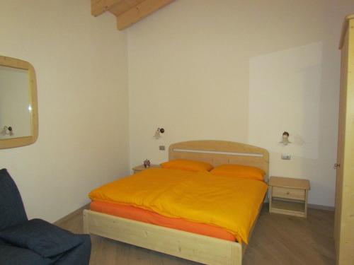 a bedroom with a bed with an orange blanket at Agritur Maso Bornie in Grauno