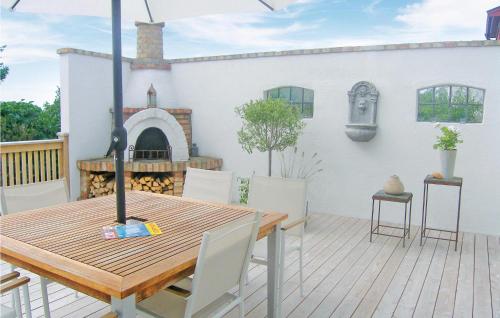 a patio with a wooden table and a fireplace at Nice Home In Beddingestrand With Sauna in Beddinge Strand