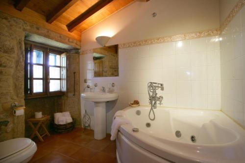 a bathroom with a tub and a sink and a toilet at A Parada Das Bestas in Pidre
