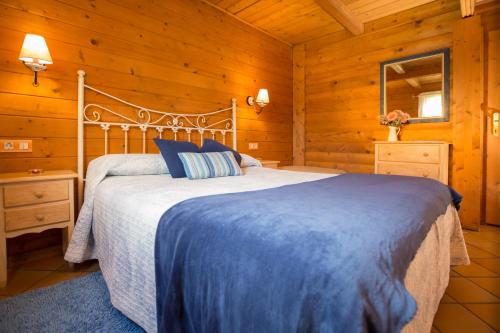 um quarto com uma cama num chalé de madeira em Cabañas de Lires em Lires